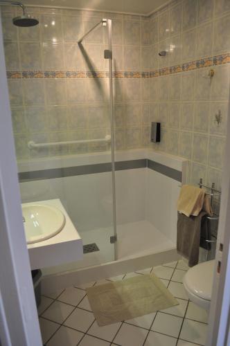 a bathroom with a shower and a tub and a sink at Logis Hotel au tambour in Reims