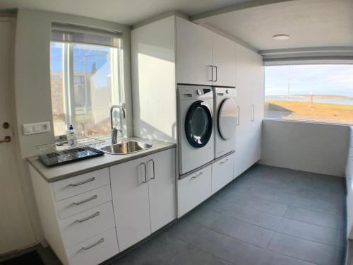 uma cozinha com um lavatório e uma máquina de lavar roupa em Waterfront Fjord House em Litli-Árskógssandur