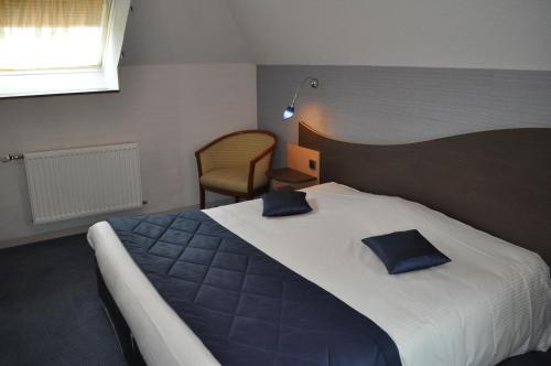 En eller flere senge i et værelse på Logis Hotel au tambour