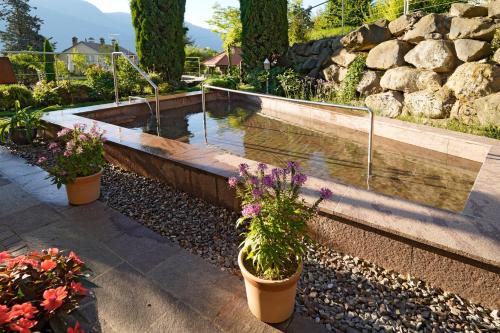 a pond in a garden with flowers in pots at Hotel Sonnenhof in Marlengo