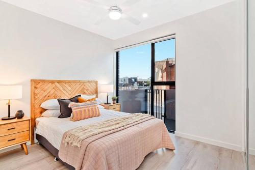a bedroom with a bed and a large window at Jewel on Jubilee - New 1 Bed Apt with Parking in Port Adelaide