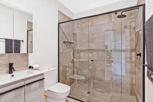 y baño con ducha, aseo y lavamanos. en Jewel on Jubilee - New 1 Bed Apt with Parking en Port Adelaide