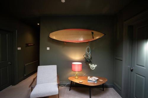 a room with a table and a surfboard on the wall at Victorian Penthouse with panoramic sea views in Ilfracombe