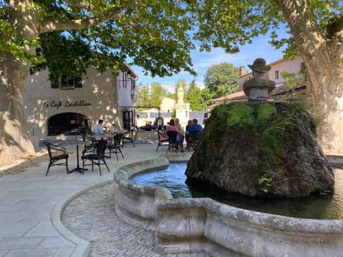 una fuente en un patio con gente sentada en las mesas en appartement calme et lumineux, en Paradou