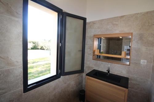 baño con lavabo, espejo y ventana en appartement calme et lumineux, en Paradou