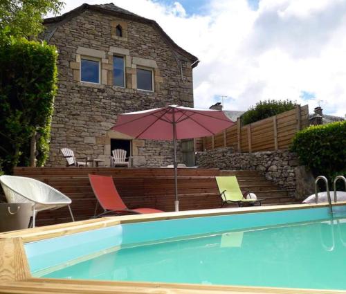 een zwembad met stoelen en een parasol voor een huis bij Maison de 4 chambres avec piscine privee jardin clos et wifi a Pierrefiche in Pierrefiche