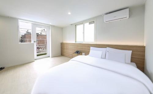 a white bedroom with a large bed and a window at Geoje Dongbeck Hotel Gohyeon in Geoje