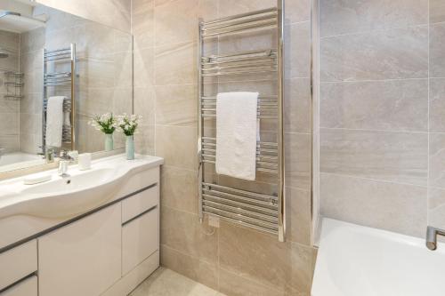 La salle de bains est pourvue d'un lavabo blanc et d'une douche. dans l'établissement ALTIDO 2-bed flat near Notting Hill, à Londres