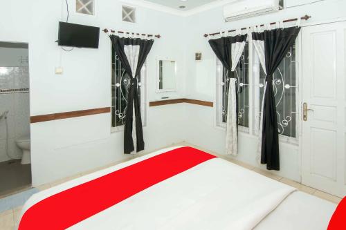 Un dormitorio con una cama roja y blanca en una habitación en Zazadior Residence Syariah near Pantai Padang Mitra RedDoorz, en Padang