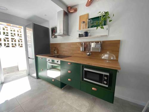 a kitchen with green cabinets and a microwave at La Casa de las Hespérides in Morro del Jable