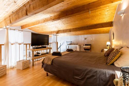 sypialnia z dużym łóżkiem i drewnianym sufitem w obiekcie Maison Gaillan Medoc w mieście Gaillan-en-Médoc