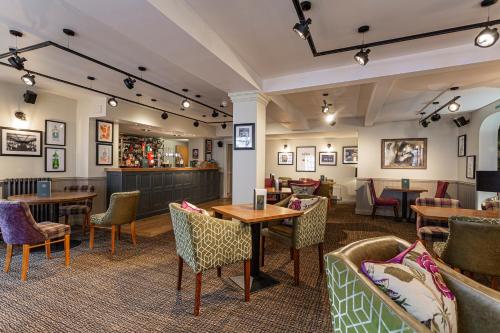 a restaurant with tables and chairs and a bar at The White Horse Hotel, Romsey, Hampshire - The Coaching Inn Group in Romsey