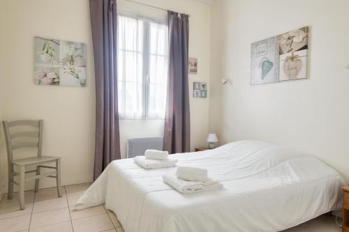 um quarto com uma cama branca e toalhas em Appartement Colombelle proche du marché et de la plage em La Couarde-sur-Mer