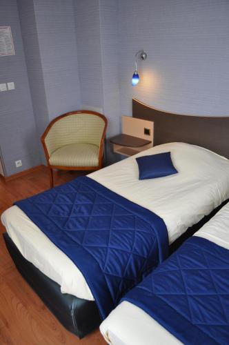 a hotel room with two beds and a chair at Logis Hotel au tambour in Reims