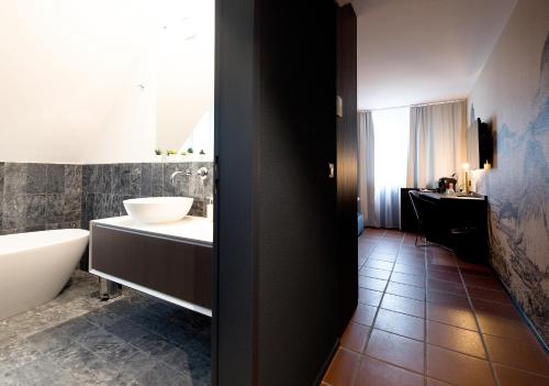 a bathroom with a tub and a sink and a toilet at Hotel Sonne Sissach in Sissach