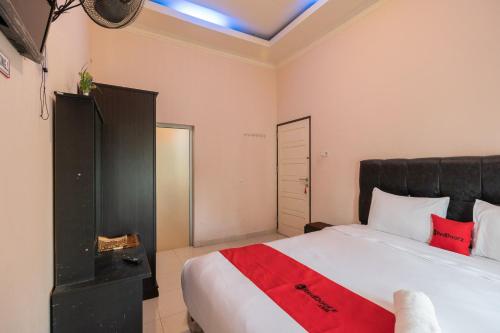 a bedroom with a large bed with a red blanket at RedDoorz Syariah at D'Ostha Residence in Bukittinggi