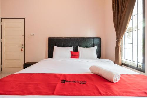 a bedroom with a large bed with a red blanket on it at RedDoorz Syariah at D'Ostha Residence in Bukittinggi