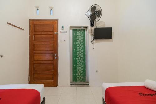 a room with two beds and a door at RedDoorz Syariah at D'Ostha Residence in Bukittinggi