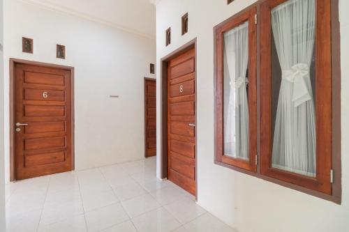a corridor with two doors and a window at RedDoorz Syariah at D'Ostha Residence in Bukittinggi