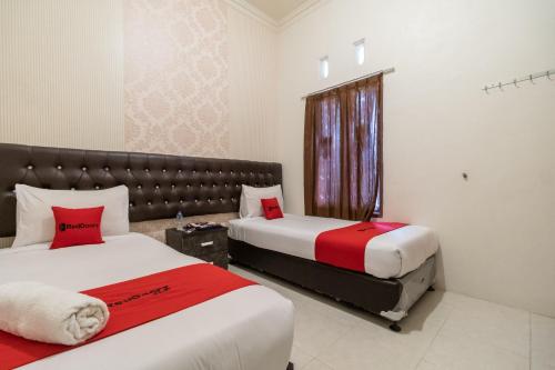 a hotel room with two beds and a window at RedDoorz Syariah at D'Ostha Residence in Bukittinggi