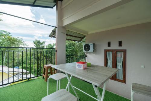 a porch with a wooden table and chairs and a balcony at RedDoorz Syariah at D'Ostha Residence in Bukittinggi
