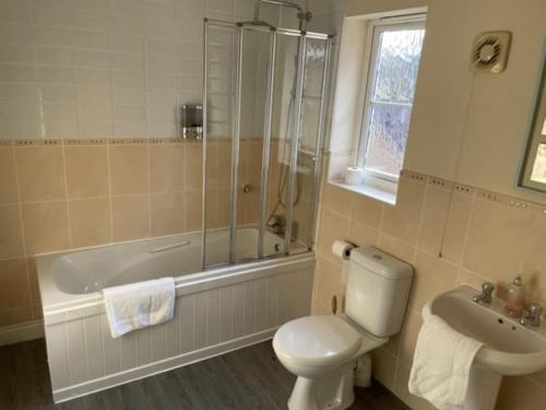uma casa de banho com um WC, um chuveiro e um lavatório. em Large 5 Bedroom Family home with parking and WI-FI em Kettering