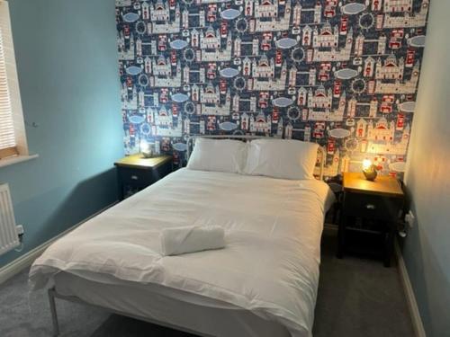 um quarto com uma grande cama branca e papel de parede em Large 5 Bedroom Family home with parking and WI-FI em Kettering
