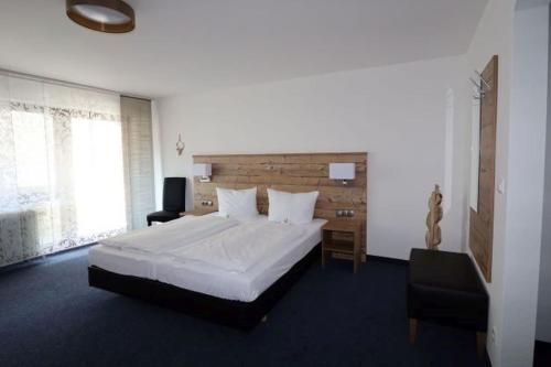 ein Schlafzimmer mit einem großen weißen Bett und einem Stuhl in der Unterkunft Hotel Garni Café Räpple in Bad Peterstal