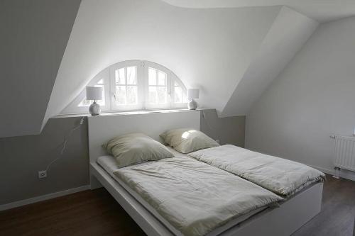 a bed in a white room with a window at Naturferienhaus 2 in Mellnitz