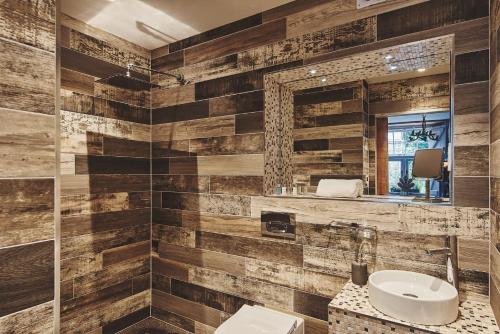 a bathroom with wooden walls and a sink and a mirror at Mimosa Cottage in Rhoose