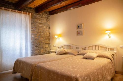 1 dormitorio con cama y pared de piedra en Garxo Apartamentos, en Isaba
