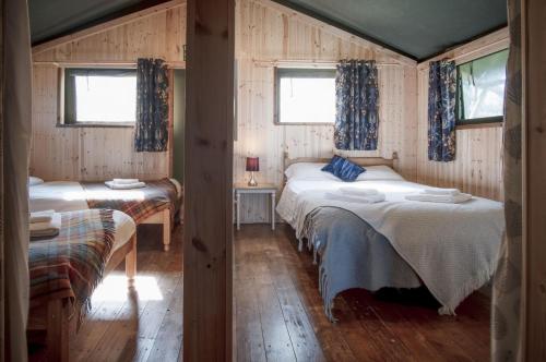 a bedroom with two beds and two windows at Three Cliffs - Safari Glamping Tent - Llangennith in Llangennith