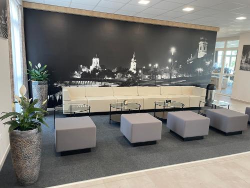 a lobby with a couch and tables and a wall at Gyirmót Sport & Wellness Hotel in Győr