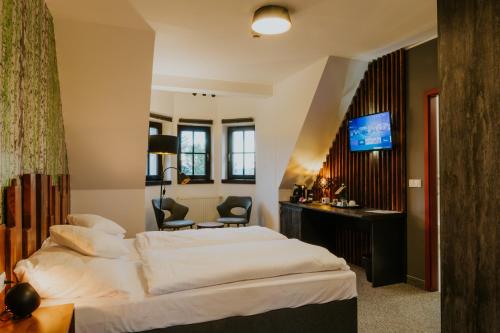 Habitación de hotel con cama, escritorio y TV. en Wellness Hotel Liberecká Výšina en Liberec