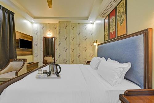 een slaapkamer met een groot wit bed en een stoel bij Hotel King's Turban in Jaipur