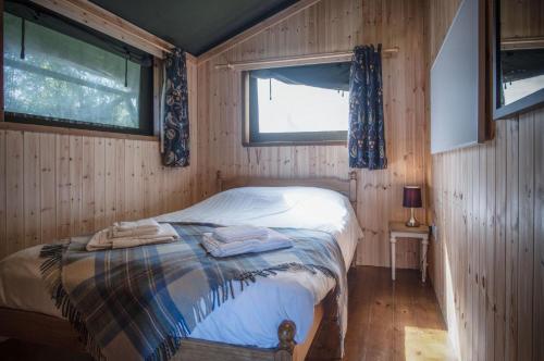 a bedroom with a bed in a wooden room at Worms Head - Safari Tent - Llangennith in Llangennith