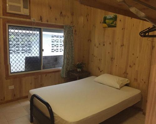 uma cama num quarto de madeira com uma janela em Happytourcairns sharehouse em Cairns