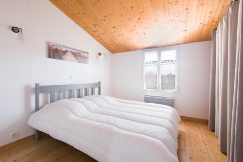 una camera da letto con un letto grande con soffitto in legno di Maison de village "Le Patio" proche du marché avec SPA a Le Bois-Plage-en-Ré