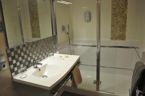 a bathroom with a sink and a shower at Logis Hotel au tambour in Reims