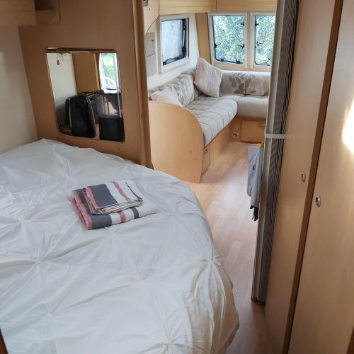 ein Schlafzimmer mit einem Bett und einem Sofa in einem Wohnwagen in der Unterkunft Les Fontenelles in Saligny-sur-Roudon