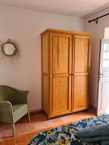 a bedroom with a wooden cabinet and a chair at Villa Al Kharoube in Essaouira