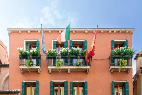 a building with potted plants and flags on it at Palazzo San Luca in Venice