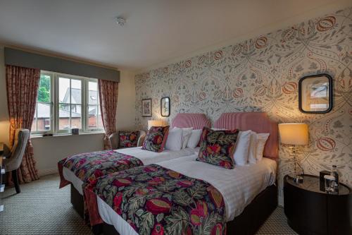a hotel room with two beds and a window at The White Horse Hotel, Romsey, Hampshire - The Coaching Inn Group in Romsey