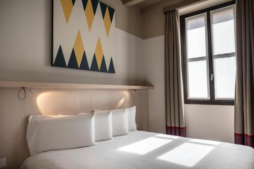 a bed with white pillows in a room with a window at Savona 18 Suites in Milan