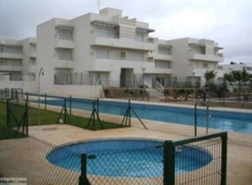 una piscina frente a un gran edificio en TOYO Apartamento golf y playa en El Toyo