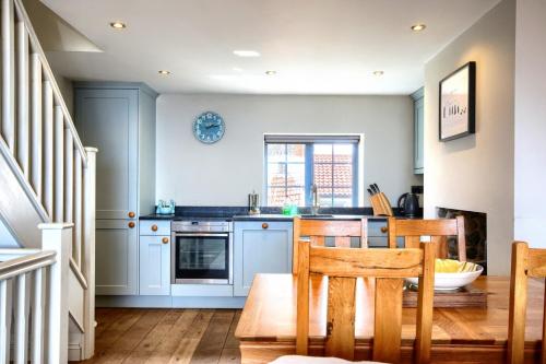 een keuken met blauwe kasten en een tafel en stoelen bij Sea Spray in Sheringham