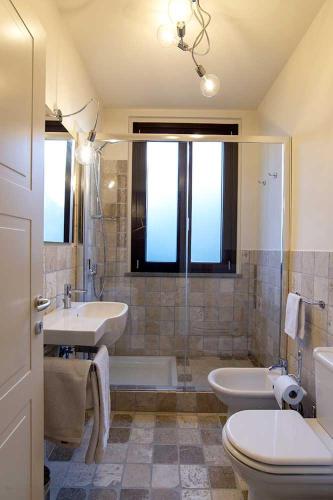 a bathroom with two sinks and a tub and a toilet at Bocelli Guest House in Laiatico