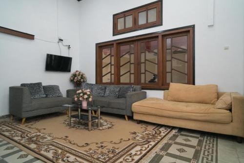 een woonkamer met 2 banken en een tv bij Urbanview Hotel Griya Surya Malang by RedDoorz in Malang