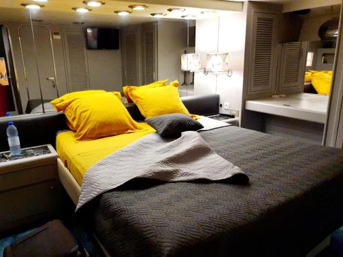 een slaapkamer met een bed met gele kussens en een spiegel bij Loc de cabines sur Yacht in Gruissan