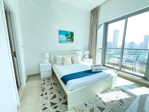 a white bedroom with a bed and a large window at HiGuests - Incredible apartment at the top of Dubai Marina in Dubai